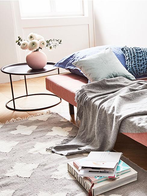 różowa rozkładana sofa w salonie przy czarnym stoliku kawowym