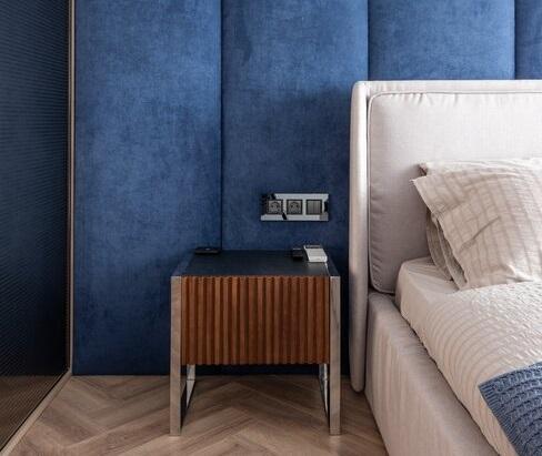 Ujęcie na wnętrze granatowej sypialni ze ścianami pokrytymi miękkim obiciem