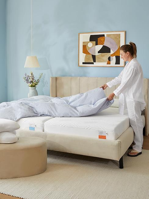 Kobieta w piżamie ścieląca łóko w jasnej sypialni