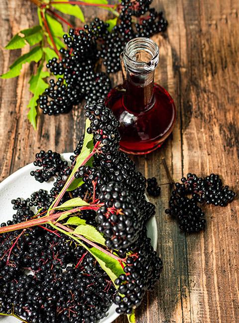 Nalewka z kwiatów czarnego bzu na stole z owocami