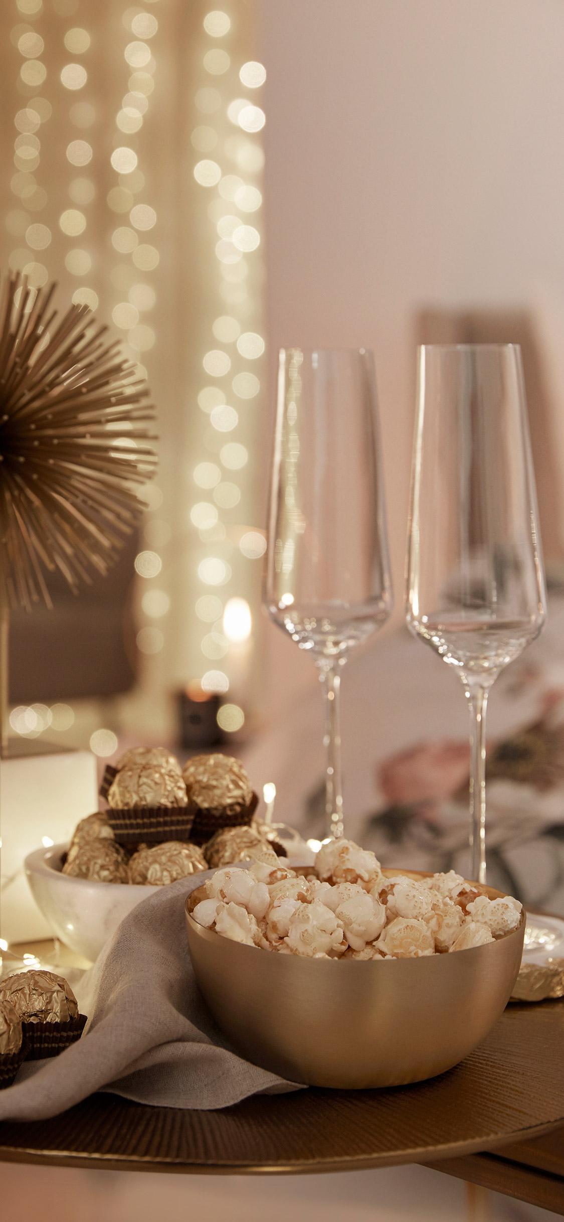 tapeta na telefon przedstawiająca kieliszki na sylwestra na tle przytulnej sypialni