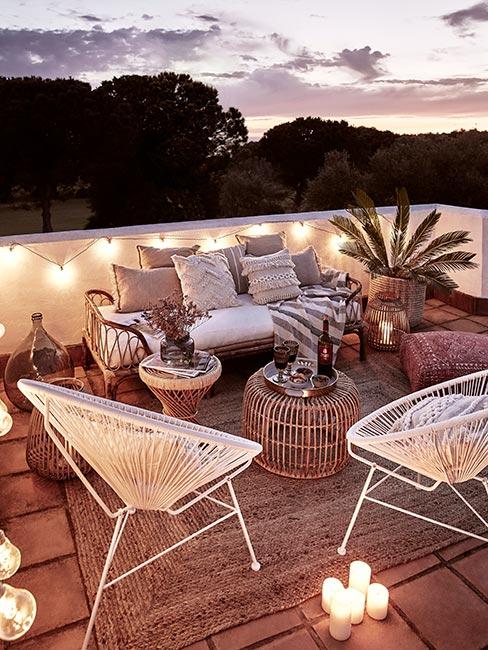 Balkon w stylu boho z plecionymi krzesłami i małą sofą z dekoracyjnymi poduszkami