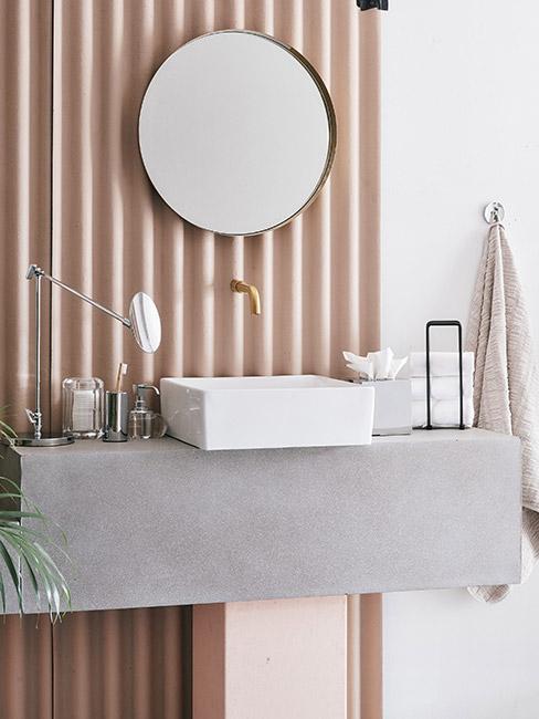 Aranżacja łazienki z pastelowym. brzoskwiniowym kolorze z grubym szarym blatem i prostokątną umywalką