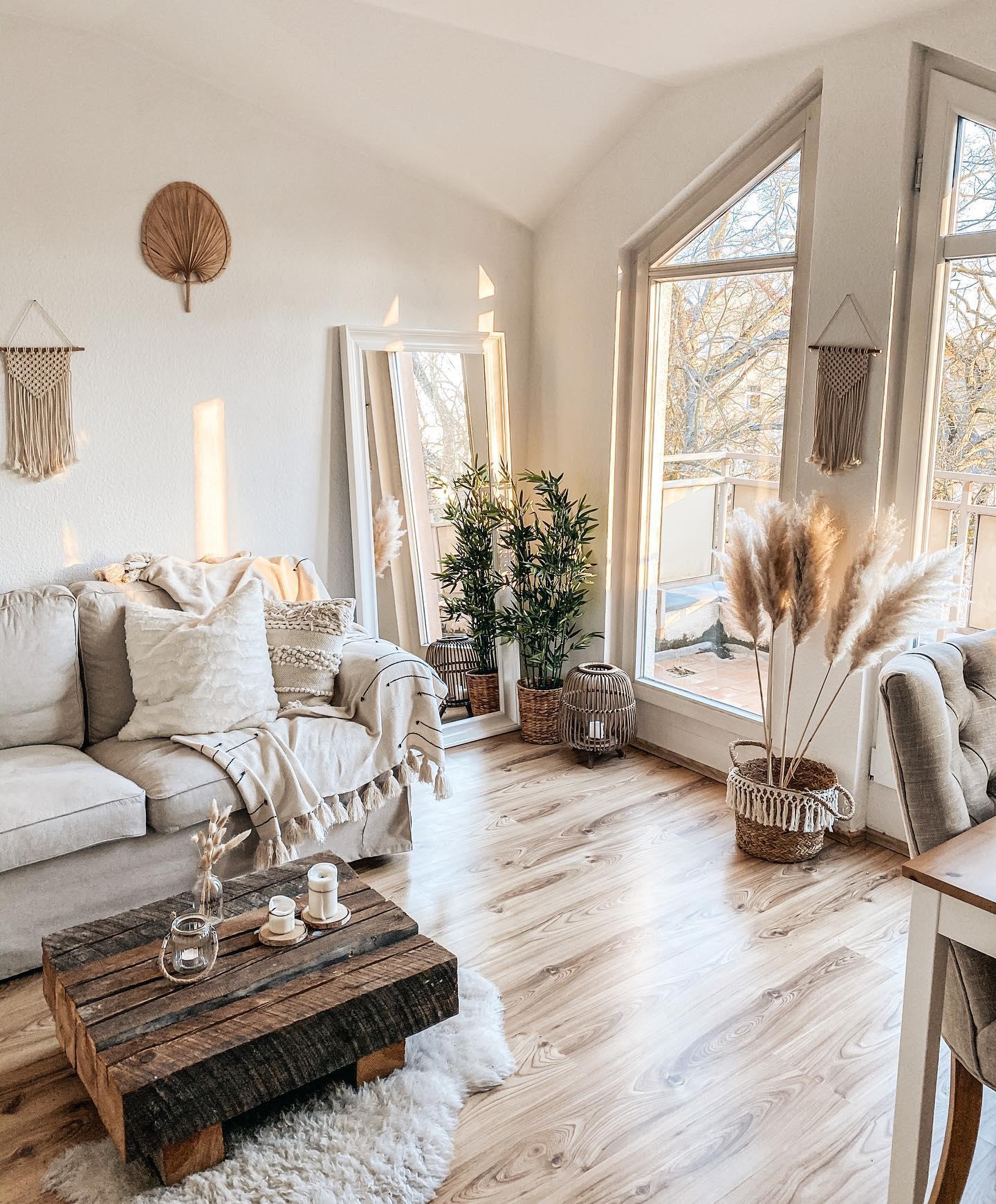 Jasny salon w stylu boho z dekoracjami na ścianie i suszonymi trawami