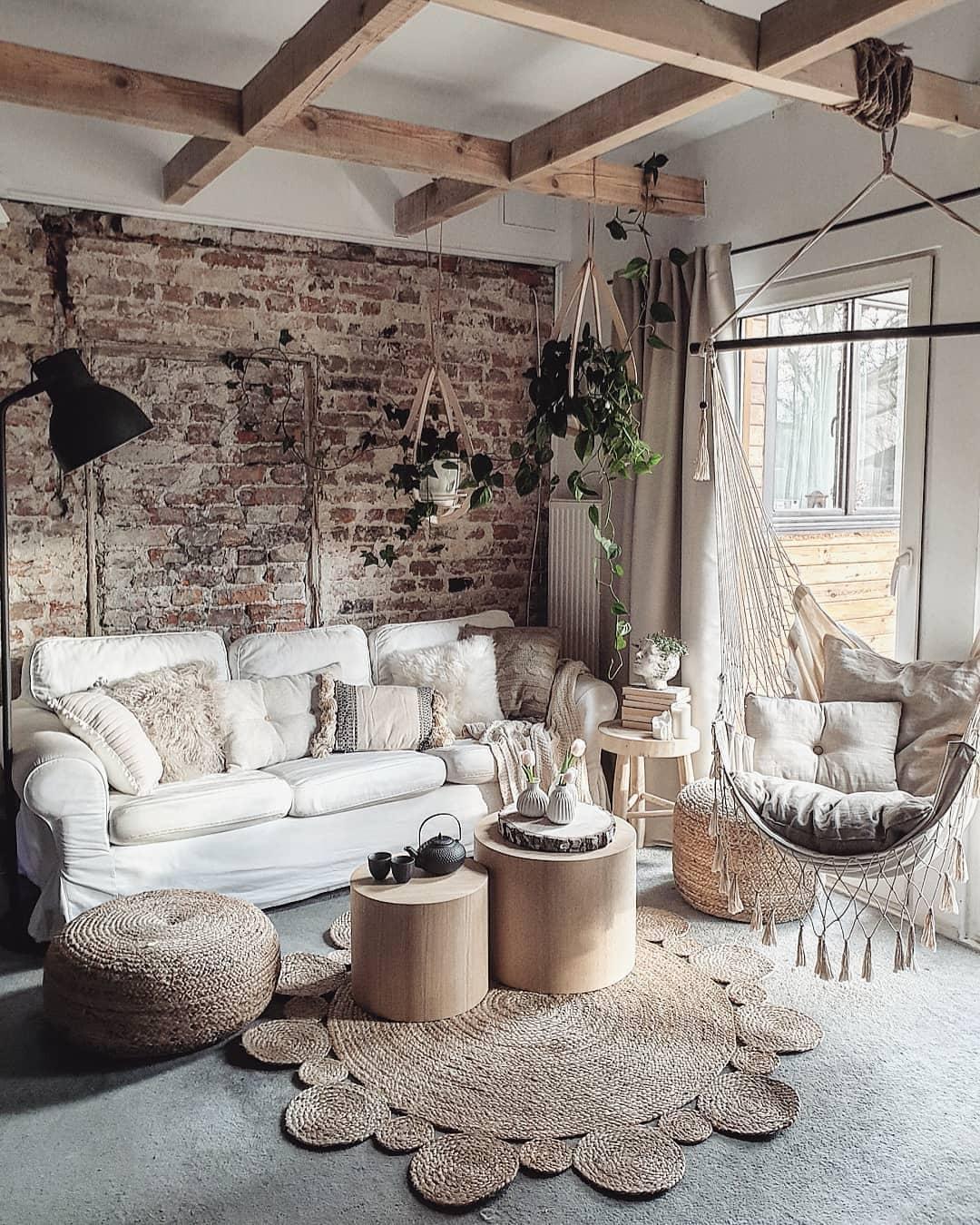 Mały salon w stylu boho z białą sofą i ceglaną ścianą z podwieszanym krzesłem