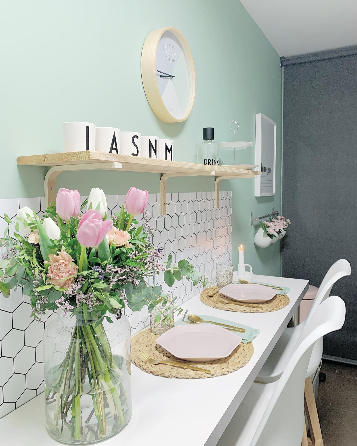 Pastelowa kuchnia z seledynową ścianą i bukietem jasnych kwiatów