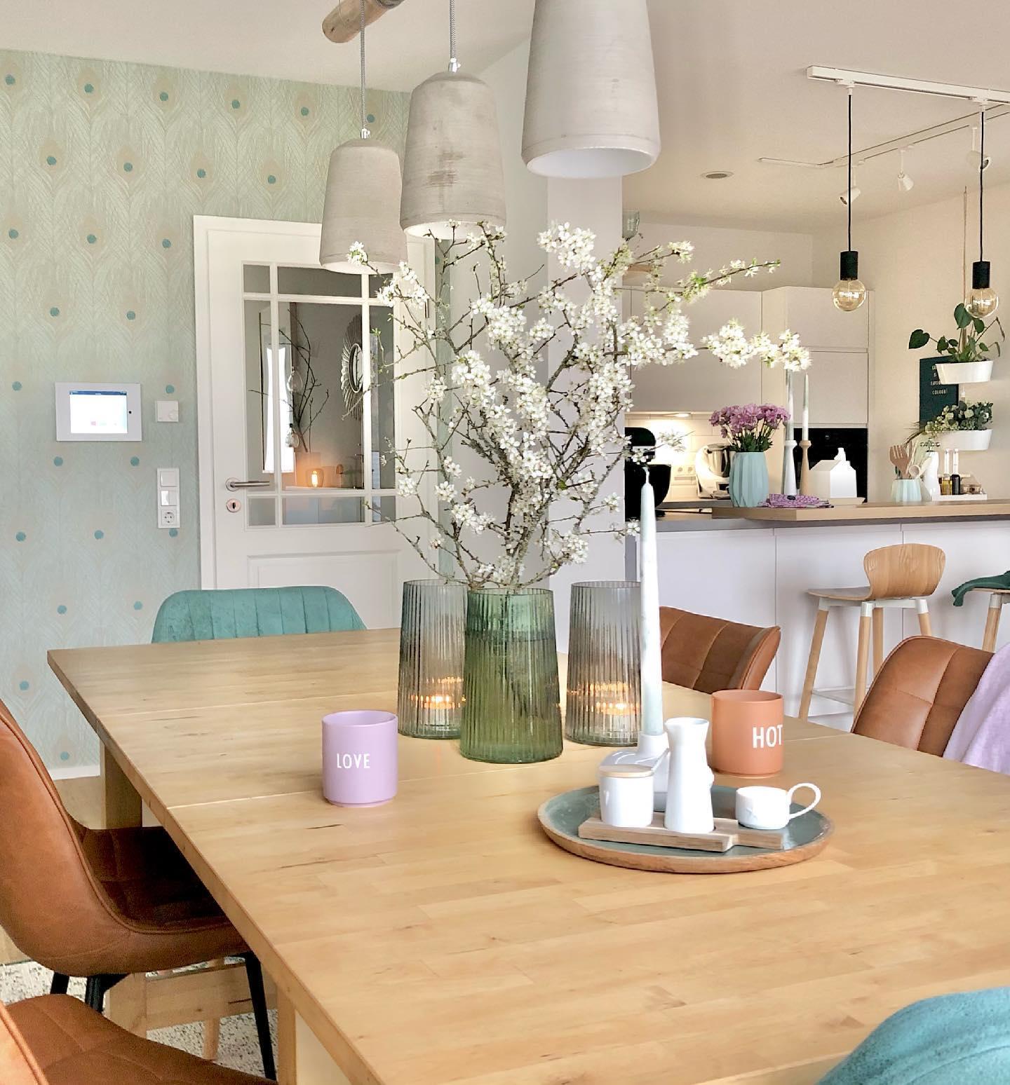 Pastelowa jadalnia z kolorowymi krzesłami i seledynową ścianą