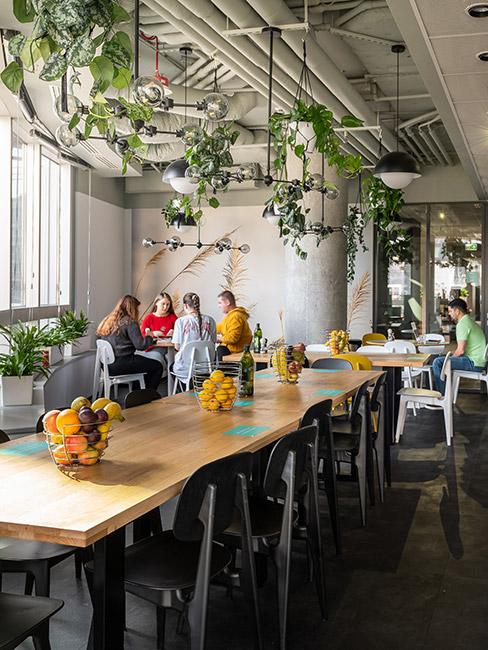 Przestrzeń kuchenna w coworking z dużymi stołami i roślinami