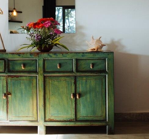 Zielona szafa, na której stoi doniczka z czerwonymi kwiatami