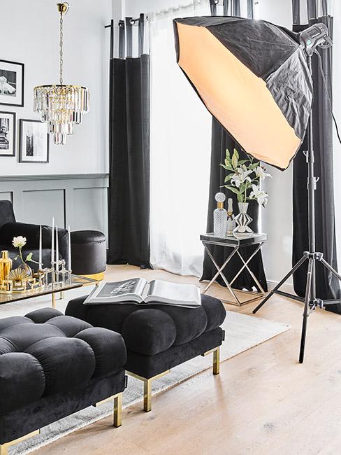 Salon czarnymi pikowanymi meblami z aksamitu na złotych nóżkach i lampami typu reflektor