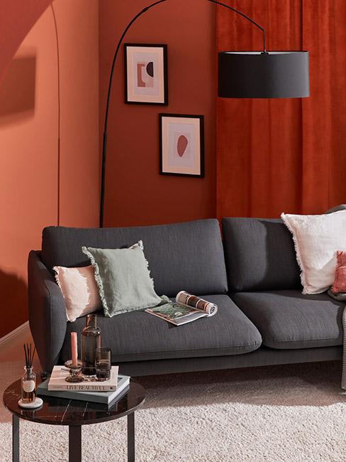 Salon z ciemną sofą w kolorze antracytu na tle ściany w kolorze terakoty