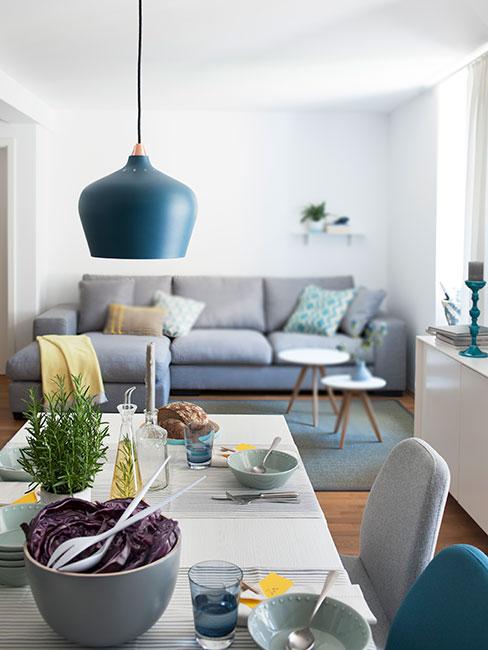 Salon z jadalnią w stylu skandynawskim z szarą sofą i dekoracjami w kolorze morskim
