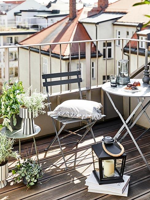 mały balkon w bloku ze szarymi składanymi meblami na drewnianej podłodze
