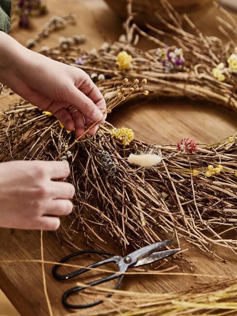 zbliżenie na ręce dekorujące wieniec wielkanocny bazimi kotkami