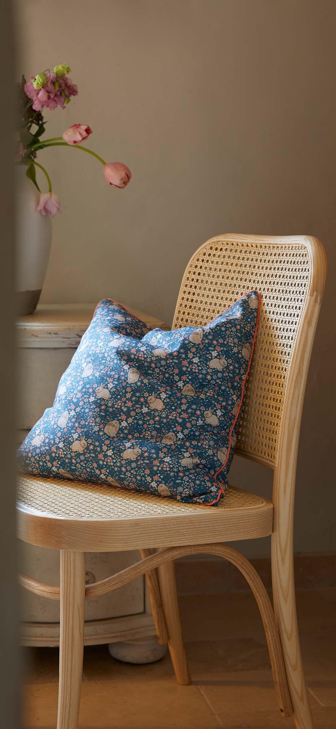 tapeta wiosenna na telefon przedstawiająca krzesło z rattanu z wiosenną poduszką