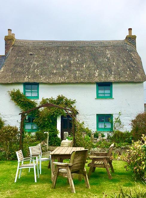 dom w stylu angielskim z ogrodem, a w nim stół i krzesła ogrodowe
