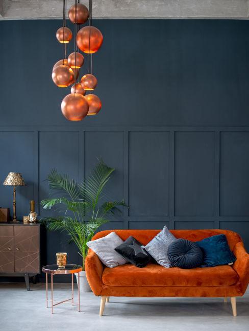 Ceglasta sofa z aksamitu na tle ciemnoniebieskiej ściany