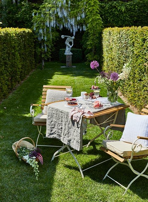 stolik i krzesła ogrodowe w stylu francuskim z naczyniami i wazonem z kwiatami na stole