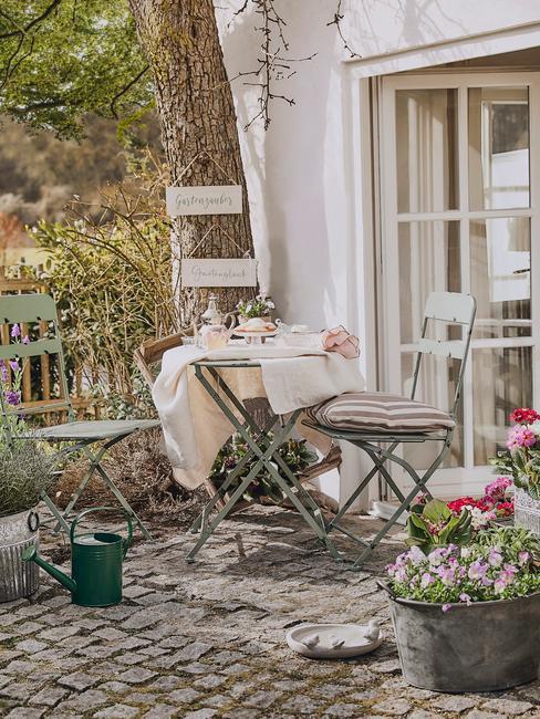 stolik i krzesła ogrodowe w stylu francuskim z naczyniami i wazonem z kwiatami na stole