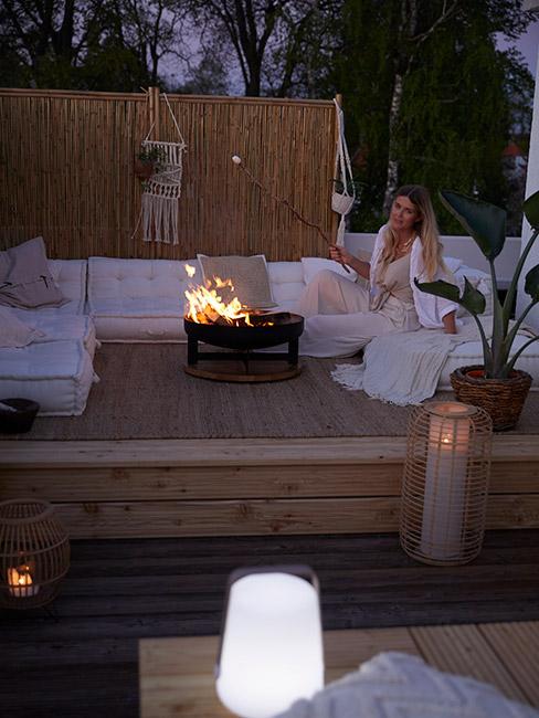 kobieta piecząca pianki w palenisku na tarasie