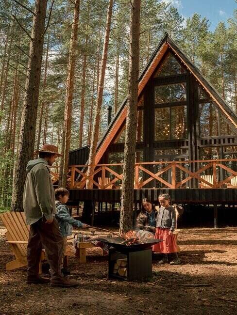 rodzina urządzająca ognisko przed domkiem w lesie