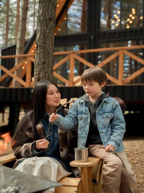 kobieta z chłopcem siedzący na krześle ogrodowym przed domkiem