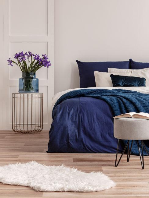 jasna sypialnia z grantową pościelą i fioletowymi kwiatami