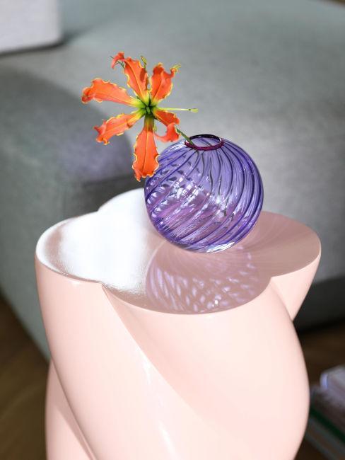 szklany okrągły wazon w kolorze fioletowym na różowym stoliku