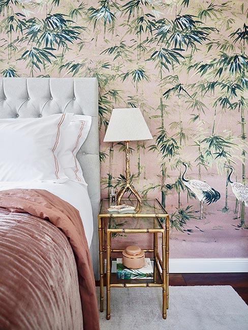 sypialnia z wzorzystą tapetą i różową, aksamitną narzutką