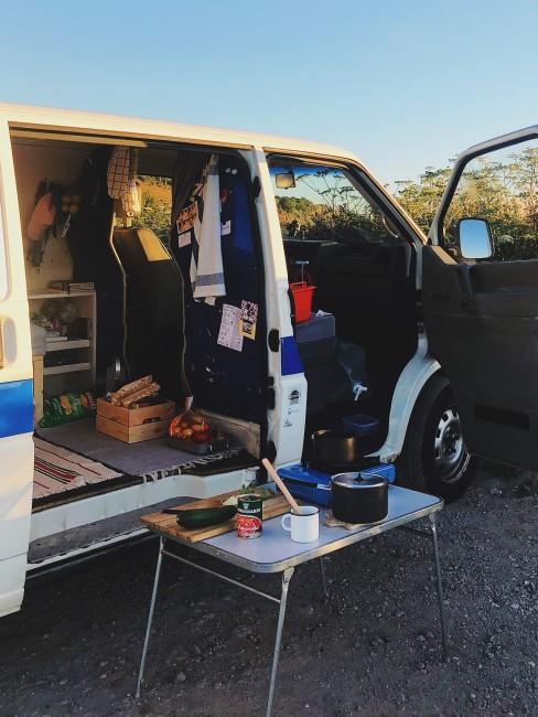 otwarty kamper i rozstawiony przed nim stolik