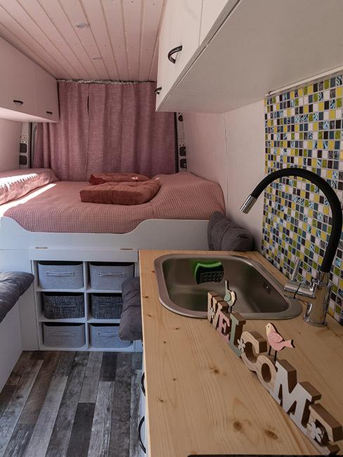 kamper w środku sypialnią w różowym kolorze i zielonymi płytkami w części kuchennej