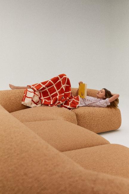 Kobieta leżąca na sofie i czytająca książkę