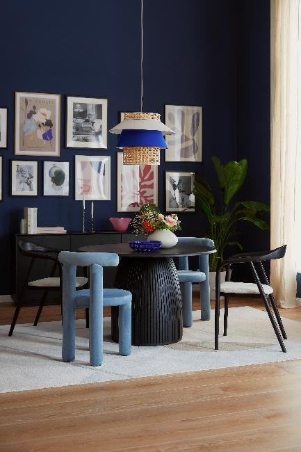 Jadalnia z czarną ścianą i galarią zdjęć. W centrym stoł z bukietem kwiatów w wazonie