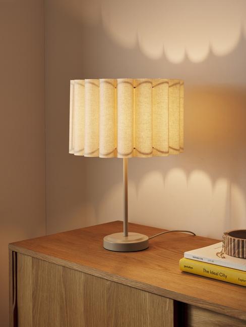 Dekoracyjna lampa z falowanym koszem na komodzie