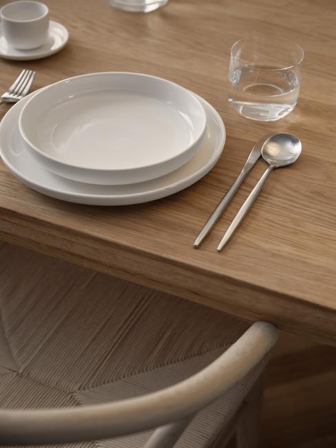 Drewniany stół nakryty białą, porcelanową zastawą
