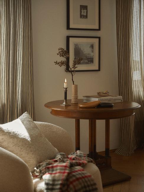 Przytulny kącik z małym stolikiem, świecją i kompozycją w wazonie