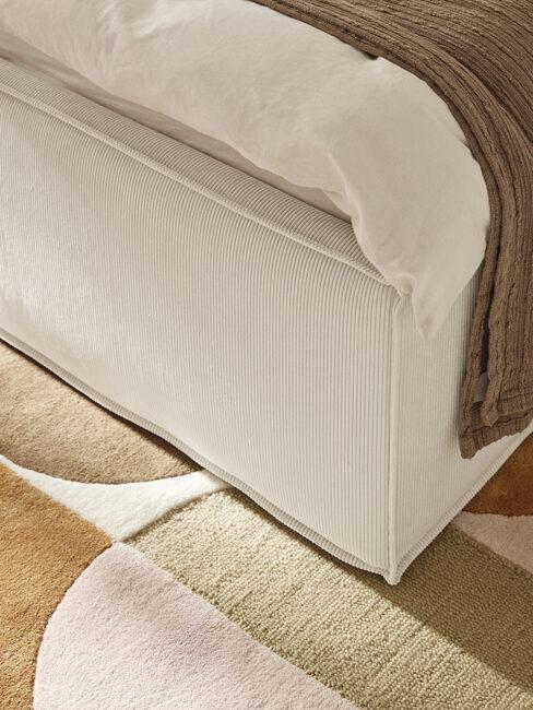 Zbliżenie na krawędź łóżka i dywan we wzory