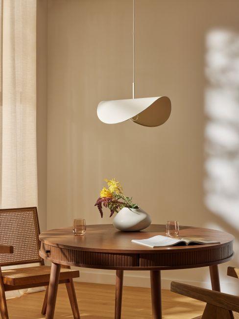 Spring dining table with round wooden table, sculptural pendant light and ceramic vase with flowers