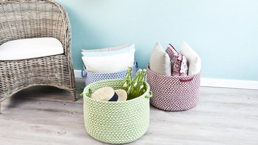 rieten fauteuil tegen pastelkleurige wand