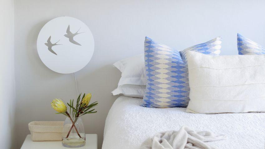 radiogestuufde wekker met vogels naast lichtkleurig bed