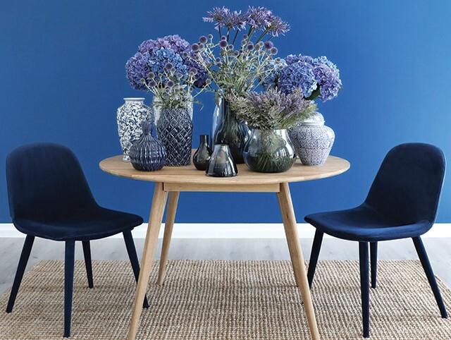 Blauwe eetkamerstoelen aan ronde houten tafel