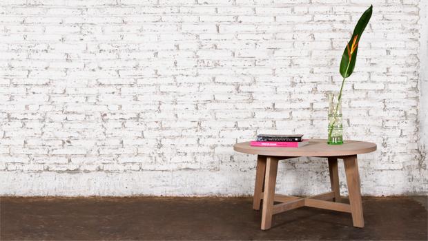 Ronde robuuste houten landelijke salontafel voor een witte betonnen muur