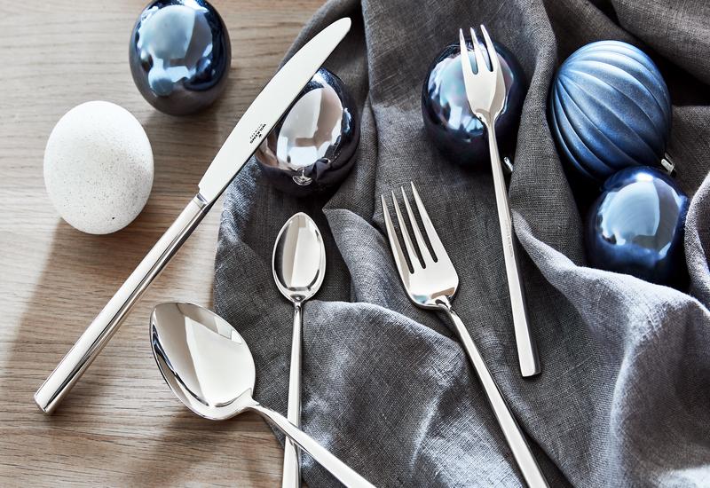 Blauwe kerstballen tussen zilver bestek