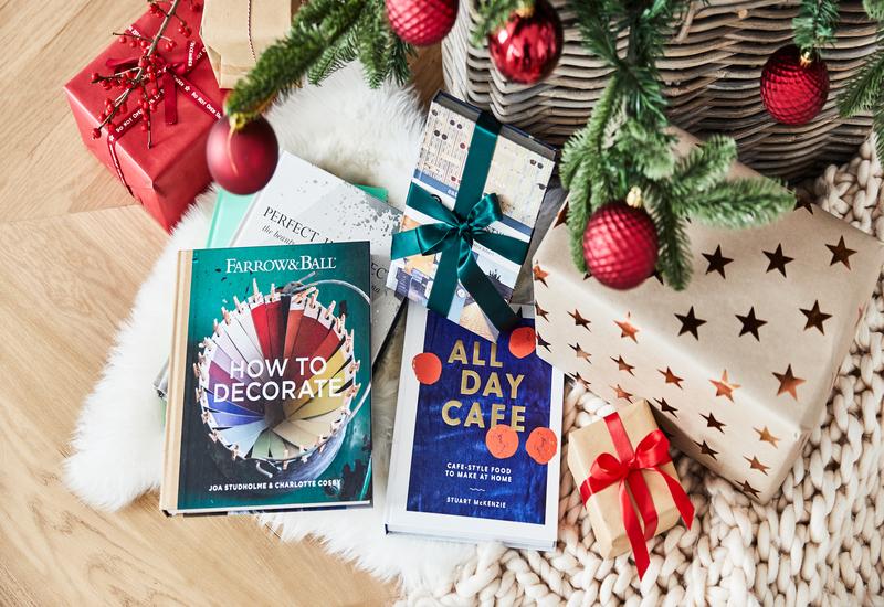 Plastic kerstballen aan een kerstboom met boeken eronder