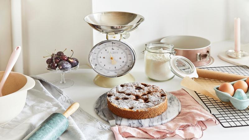 een keukenweegschaal, bloem en een taart in de keuken