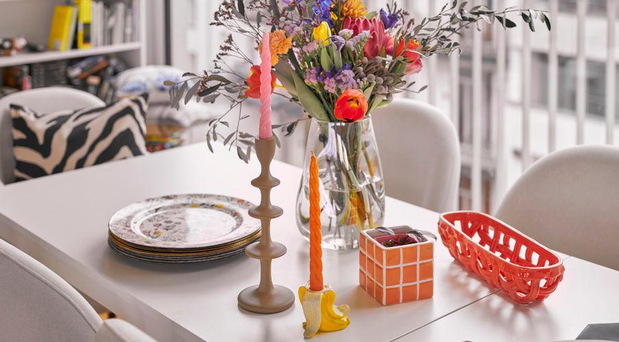 gedraaide kaarsen met bloemen op een eettafel in een kleurrijk interieur
