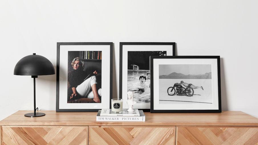 een houten dressoir met photos en een paddenstoel lamp