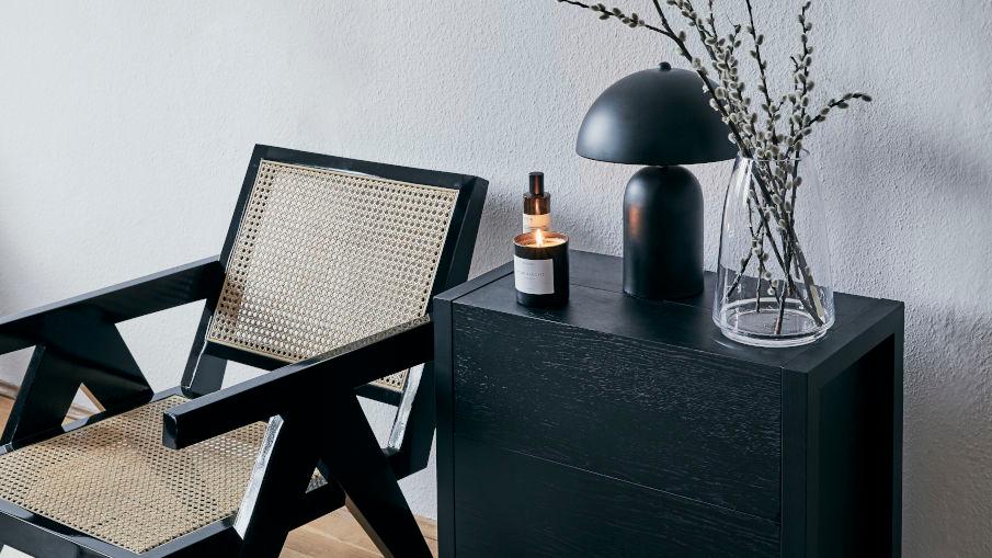 zwarte mushroom lamp op een dressoir en naast een stoel