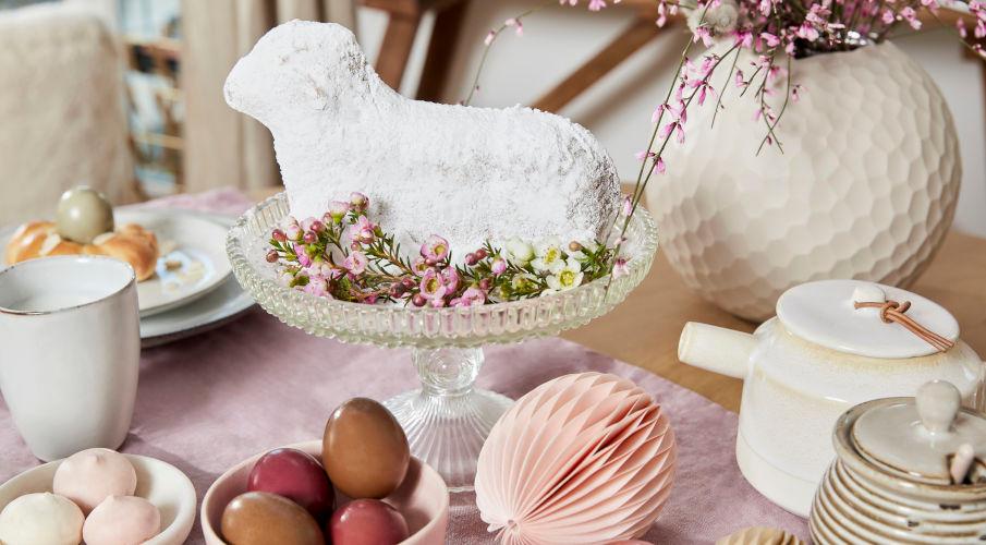 paaskuikens en paasdecoratie op tafel met een taart in schaapvorm