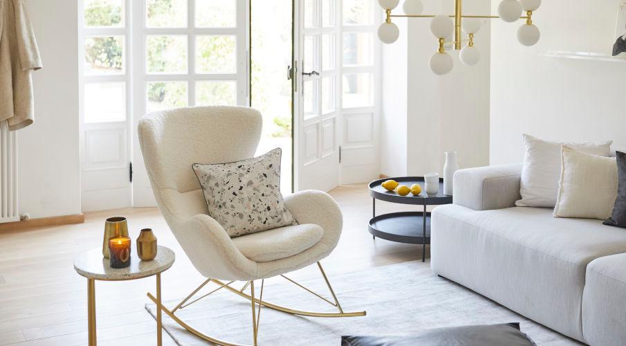 een woonkamer met een teddy stoel, zwarte salontafel, en grijze bank